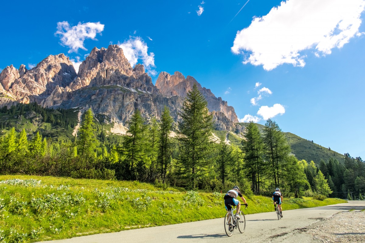 Two road cyclists on an alpine road with a mountain in the backdrop